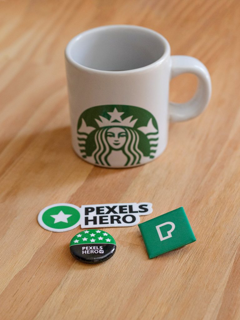 A Starbucks Cup near the Pexels Pin and Sticker.