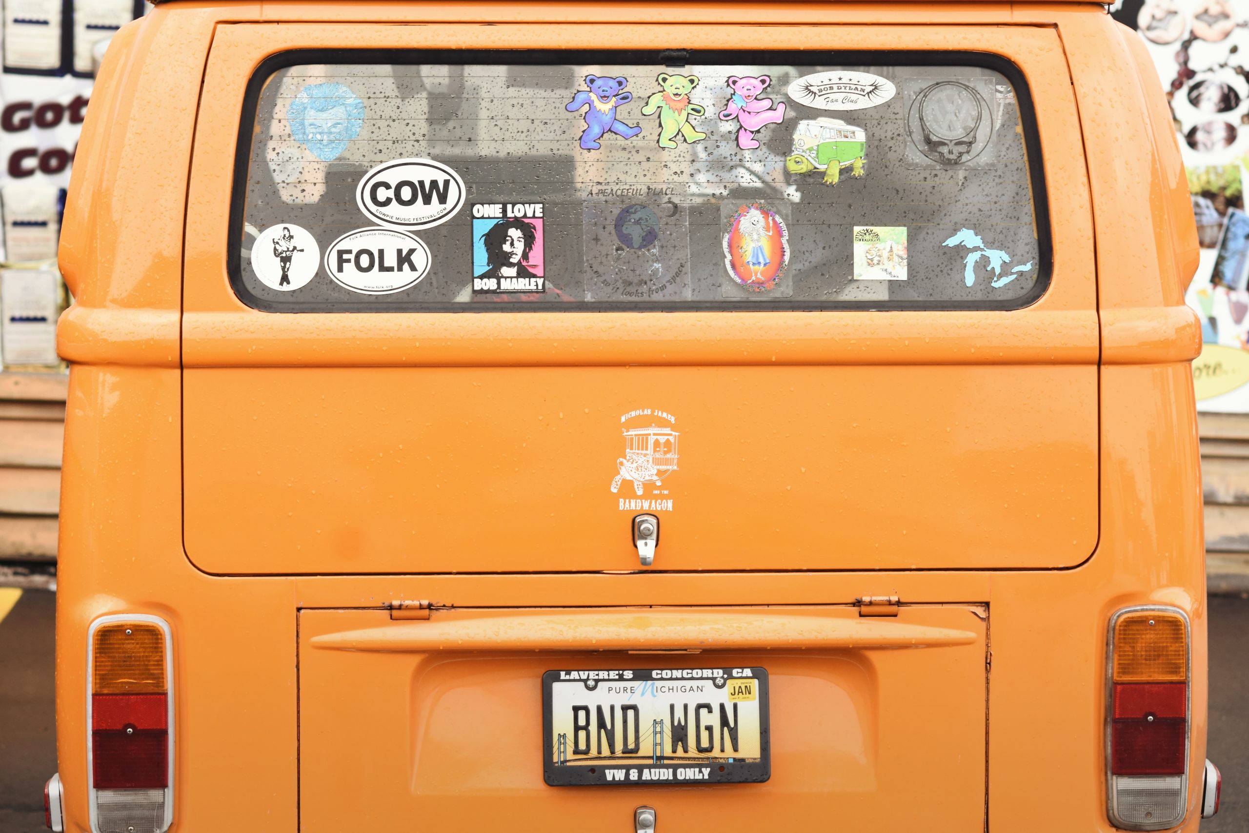 back window of an orange van covered in old stickers.