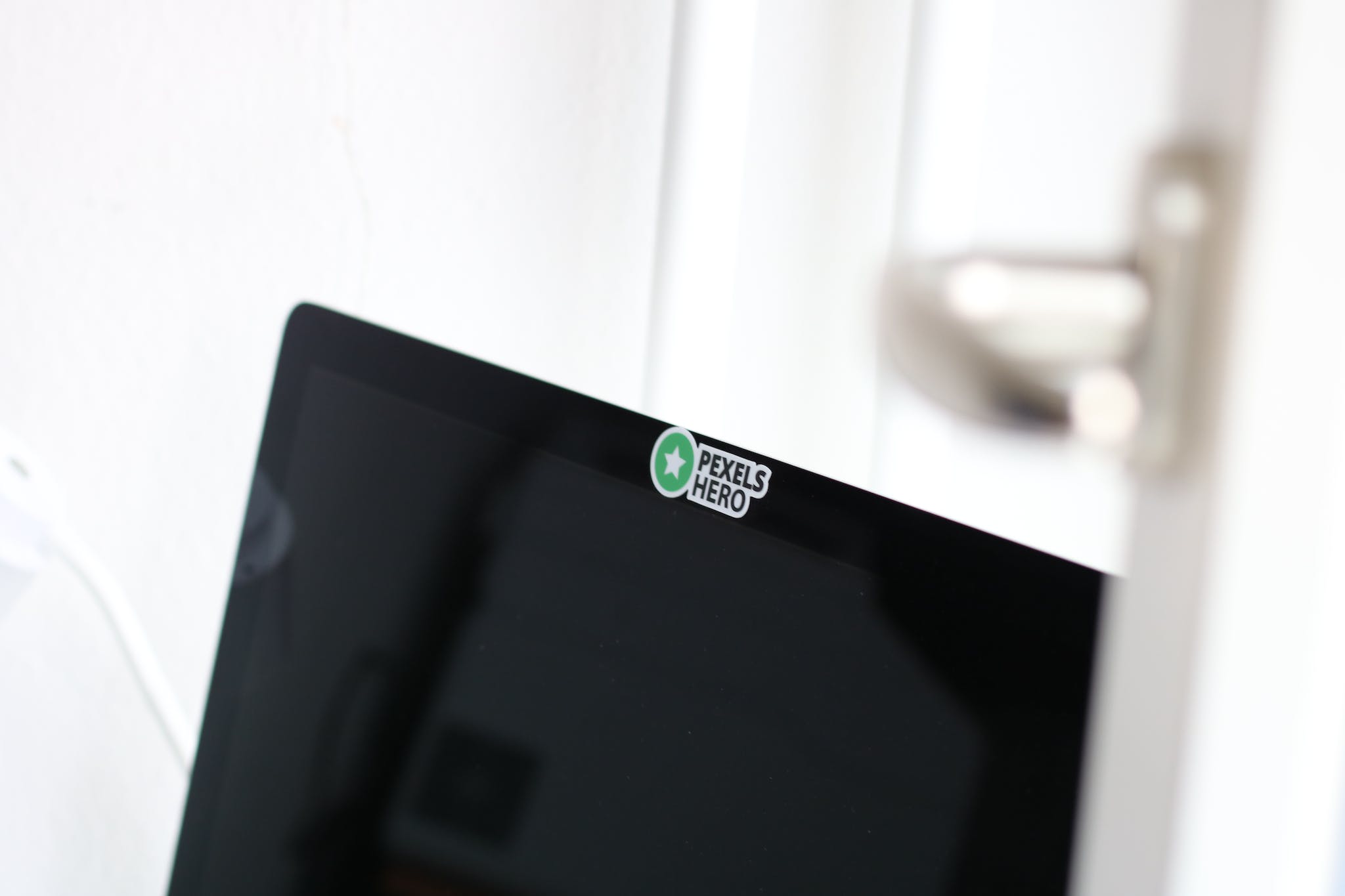 Closeup Photo of Opened Black Laptop Computer With Pexels Hero Sticker over the camera.