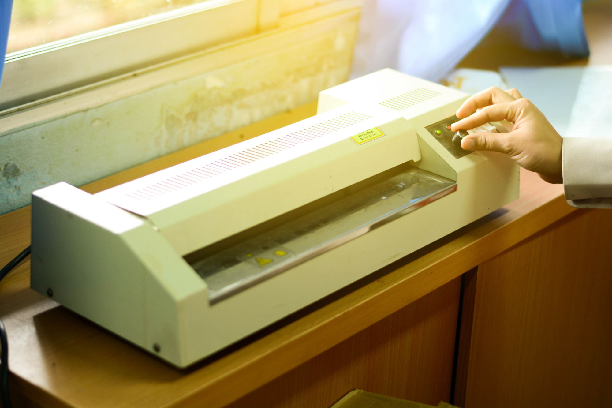 hand touching the dial on a lamination machine.