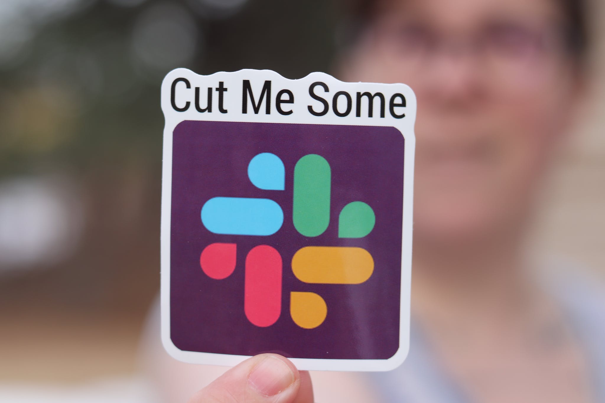 A Hand Holding a Colorful  Slack Sticker.